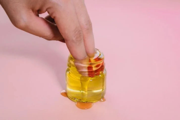 손가락을 투명한 노란색 젤 형태의 러브젤에 담근 모습 — 점도와 사용감을 보여주는 러브젤 가이드 이미지